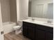 Modern bathroom boasts dual sink vanity with dark cabinetry and tiled shower at 32128 Eastern Redbud Br, San Antonio, FL 33576
