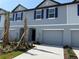 New two-story townhome with blue shutters and a one-car garage, complemented by palm trees at 32128 Eastern Redbud Br, San Antonio, FL 33576