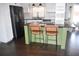 Modern kitchen with a green island, black appliances, and white subway tile backsplash at 821 Silver Springs Nw Ter, Port Charlotte, FL 33948