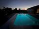 Dusk view of a swimming pool with bright blue lighting and a house in the background at 821 Silver Springs Nw Ter, Port Charlotte, FL 33948