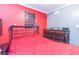 Bedroom features a vibrant red accent wall, wood floors, and comfortable furnishings at 5710 92Nd N Ter, Pinellas Park, FL 33782