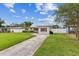 Charming single-story home with a well-manicured lawn, palm trees, and a white picket fence at 5710 92Nd N Ter, Pinellas Park, FL 33782
