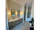 Bright bathroom featuring double sinks, neutral cabinets, decorative sconces, and large walk-in shower at 608 Bittner Blvd, Nokomis, FL 34275