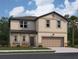 Two-story home featuring beige siding, a two-car garage, and manicured landscaping at 14673 Italy Ave, Dade City, FL 33523