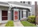 Close-up of the red front door of the townhouse with black shutters and a well-manicured lawn at 232 Countryside Key Blvd, Oldsmar, FL 34677