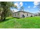 Large, grassy backyard showing the house's exterior with lush green lawn and some landscaping at 2919 Cascabel Ter, North Port, FL 34286