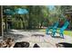 Outdoor fire pit on a brick patio with turquoise Adirondack chairs, perfect for relaxing in nature at 5148 Cyril Dr, Dade City, FL 33523