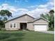 Inviting single-story home with a two-car garage, neutral stucco, horizontal siding, stone accents, and manicured lawn at 14684 Italy Ave, Dade City, FL 33523