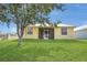 Expansive backyard with lush green lawn and a charming yellow home featuring a screened patio at 6412 Coquina Island Cv, Apollo Beach, FL 33572