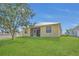 Spacious backyard with lush green lawn and a charming yellow home featuring a screened patio at 6412 Coquina Island Cv, Apollo Beach, FL 33572