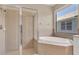 This bathroom features a glass shower, tile flooring and walls, and a separate tub under a window at 6412 Coquina Island Cv, Apollo Beach, FL 33572