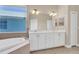 Bright bathroom with a double sink vanity, soaking tub, and a large window for natural light at 6412 Coquina Island Cv, Apollo Beach, FL 33572