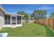 Well-maintained backyard with green grass, a wooden fence, and an enclosed sunroom at 806 Rocky Mountain Ct, Valrico, FL 33594