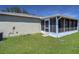 View of a well-kept backyard with green grass and an enclosed sunroom area at 806 Rocky Mountain Ct, Valrico, FL 33594