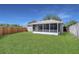 View of backyard, showcasing the spacious lawn and enclosed sunroom attached to the house at 806 Rocky Mountain Ct, Valrico, FL 33594