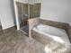 Bathroom features a tiled floor, walk-in shower, and soaking tub with tiled accents at 10768 Carloway Hills Dr, Wimauma, FL 33598