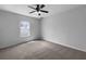 Comfortable bedroom with a ceiling fan, neutral carpet, and natural light from a single window at 10768 Carloway Hills Dr, Wimauma, FL 33598