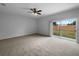 Bright bedroom featuring a ceiling fan, neutral carpet, and access to backyard through sliding glass door at 10768 Carloway Hills Dr, Wimauma, FL 33598