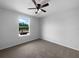 Cozy bedroom features carpet flooring, a ceiling fan, and a bright window with neighborhood views at 10768 Carloway Hills Dr, Wimauma, FL 33598