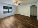 Spacious living room featuring wood-look flooring, a ceiling fan, and a bright window at 5383 Magdalene Way, Zephyrhills, FL 33541