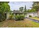 Single-story home featuring lush landscaping, a driveway, and a cozy front porch at 5651 Kelly N Dr, St Petersburg, FL 33703