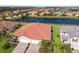 Aerial view of a home with a tile roof, 3-car garage, and landscaped yard near a lake at 2532 Avolet Ct, Lakewood Ranch, FL 34211