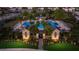Aerial view of community pool, clubhouse, palms, and landscaping, at dusk with walkways and lighting at 2532 Avolet Ct, Lakewood Ranch, FL 34211