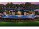 Community water feature at dusk with lush landscaping, flowering plants, stone benches, and blue water at 2532 Avolet Ct, Lakewood Ranch, FL 34211