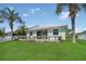 Lawn and rear view of home with a wooden deck and patio, lush lawn, and palm trees at 530 Bimini Bay Blvd, Apollo Beach, FL 33572