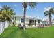 Back exterior of home with a wooden deck, lush lawn, and complemented by swaying palm trees at 530 Bimini Bay Blvd, Apollo Beach, FL 33572