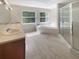 Bright bathroom with double sinks, soaking tub, and glass enclosed shower at 915 Woodbridge Ct, Safety Harbor, FL 34695