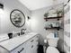 Well-lit bathroom with vanity, round mirror, and decorative shelves at 14146 Gulf Blvd # 3A, Madeira Beach, FL 33708