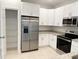 Well-lit kitchen featuring white cabinets, stainless steel appliances, and a walk-in pantry at 1160 Edinburgh St, North Port, FL 34288