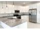 This kitchen is equipped with stainless steel appliances, granite countertops, white cabinets, and modern pendant lighting at 1160 Edinburgh St, North Port, FL 34288
