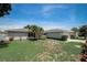 Charming single-story home featuring a well-maintained lawn and mature landscaping under a bright blue sky at 9497 122Nd Way, Seminole, FL 33772