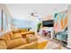 Fun living room featuring a cozy yellow sectional sofa, playful wall art, and a pool table at 9497 122Nd Way, Seminole, FL 33772