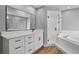 Bright bathroom features white vanity with black hardware, walk-in shower, and soaking tub at 1438 Mclin Dr, Plant City, FL 33565