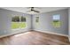 Bedroom with ceiling fan, base trim, hardwood floors and three large picture windows at 1438 Mclin Dr, Plant City, FL 33565