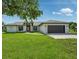 Charming single-story home with a well-manicured lawn, attached garage, and a vibrant red front door at 1438 Mclin Dr, Plant City, FL 33565