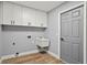 Bright laundry room features white cabinets, modern sink, sleek gray walls, and wood-look laminate flooring at 1438 Mclin Dr, Plant City, FL 33565