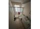 Compact bathroom featuring a shower-tub combo with glass doors, a vanity sink, and tile floors at 359 S Orchid Dr, Ellenton, FL 34222