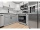 Close-up of a modern kitchen featuring stainless steel appliances, gray cabinets, and a white countertop at 3926 Helena Ne St, St Petersburg, FL 33703