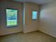 Clean bedroom with neutral tile flooring and two windows offering natural light at 27206 Adams St, Punta Gorda, FL 33983