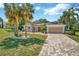 Charming home featuring a manicured lawn, mature trees, and a paved driveway leading to a two-car garage at 14680 Linden Dr, Spring Hill, FL 34609