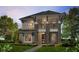 A modern two-story home boasts stone accents, a balcony, and a well-manicured lawn at 28875 Seedling St, Wesley Chapel, FL 33543