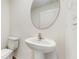 A minimalist bathroom featuring a pedestal sink, oval mirror, and a toilet set against a clean, white wall at 5329 Companion Ln, Tampa, FL 33619