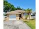 Charming stone-clad home with an attached garage, landscaped front yard, and a bright red front door at 4419 Waltham Dr, Tampa, FL 33634