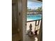 View from the bathroom to an outdoor patio, featuring a pool, lounge chairs, and lush tropical landscaping at 8252 Tecumseh Cir, Port Charlotte, FL 33981