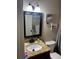 Compact bathroom with a granite-topped vanity, framed mirror, and coastal-themed decor at 1317 W Alicia Ave, Tampa, FL 33604
