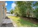 Large backyard with green lawn, concrete patio, lush trees, and partial view of fencing at 212 Citrus Landing Dr, Plant City, FL 33563
